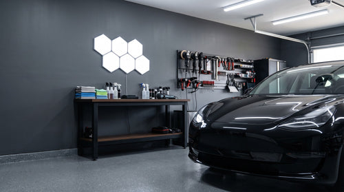 Six Aetheris Hexagon Light Panels glowing cool white above a workbench in a home garage